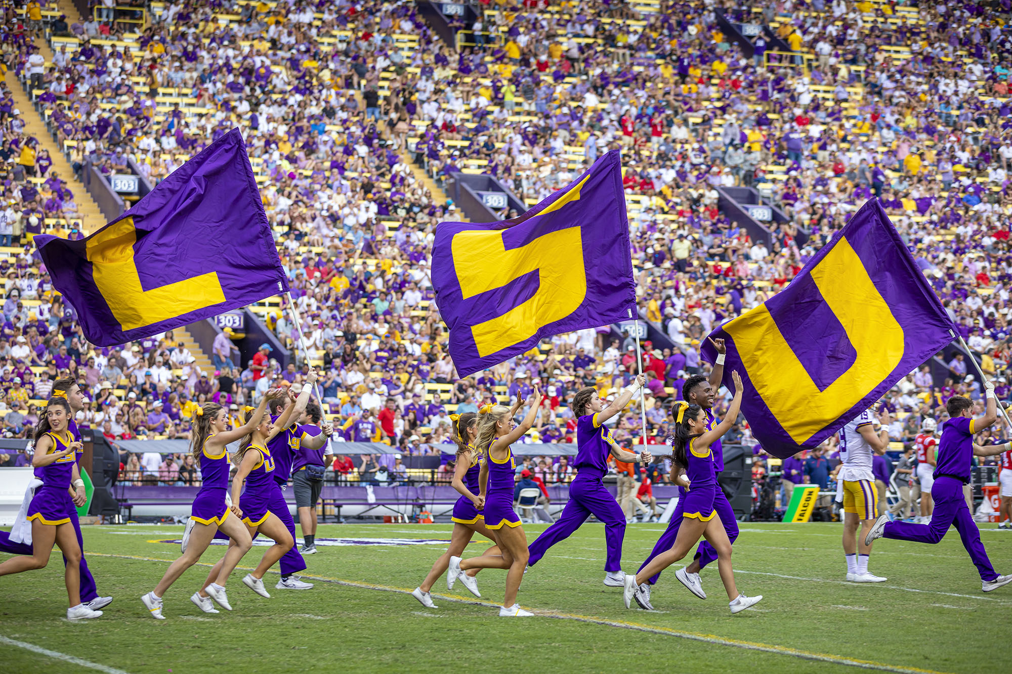 Cheerleaders running with LSU flags