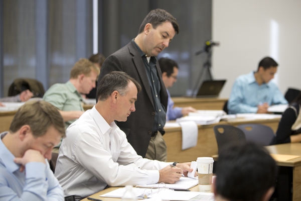 Instructor looks over students shoulder as he asks a question.